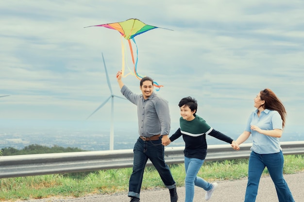 Progressive happy carefree family vacation concept flying kite with wind turbine
