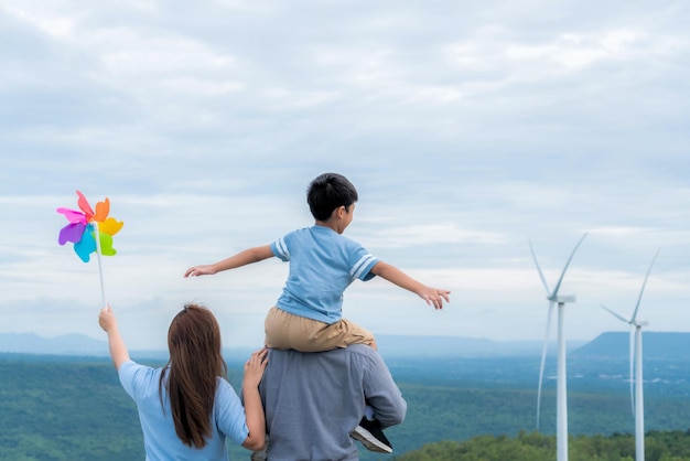 進歩的な幸せな家族は、グリーン エネルギーの概念のために風力発電所で時間を楽しむ