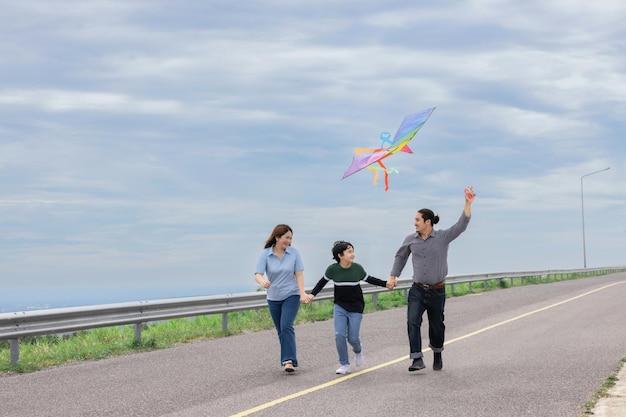 Progressive happy family vacation concept with outdoor flying kite on the road