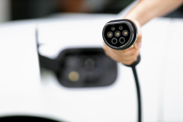 Progressive idea of focus hand pointing charging plug at camera blur background