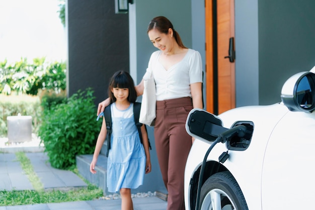 EV 자동차와 충전소를 갖춘 엄마와 딸의 진보적인 라이프스타일