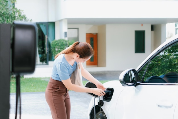 写真 進歩的な女性が自宅の充電ステーションで ev 車を充電する