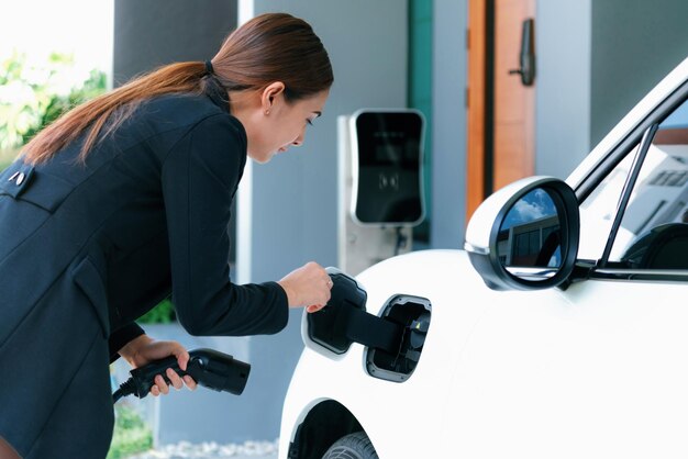 進歩的な女性が自宅の充電ステーションで EV 車を充電する