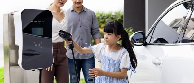 Progressive young parents and daughter living in a home with an electric car