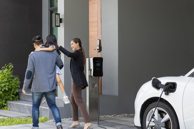 Progressive young parents and daughter living in a home with an electric car