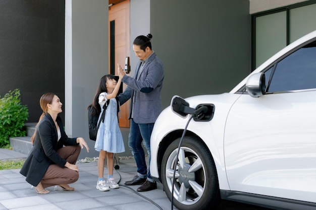 電気自動車のある家に住む進歩的な若い両親と娘