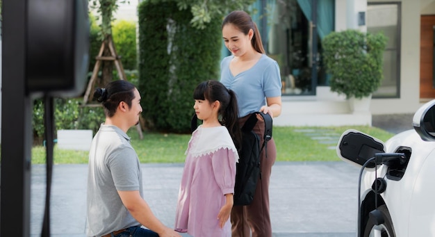 Progressive young parents and daughter living in a home with an electric car