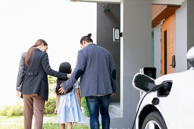 Progressive young parents and daughter living in a home with an electric car