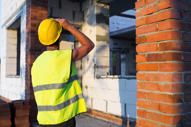 Projectarchitect staat in de buurt van de bouwplaats van een huis met de muur