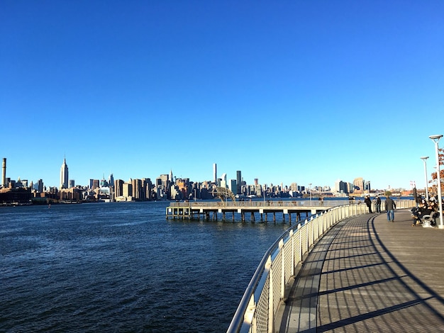 Promenade in city against clear blue sky