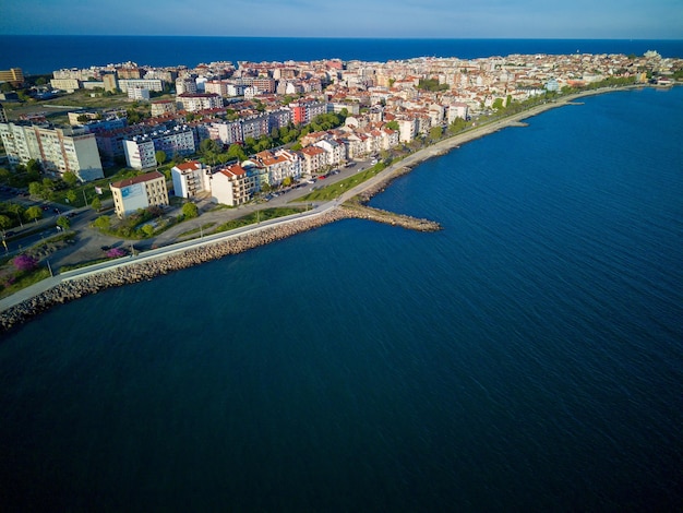 Прогулка с людьми, гуляющими у Черного моря на фоне города Поморие в Болгарии под облачным небом