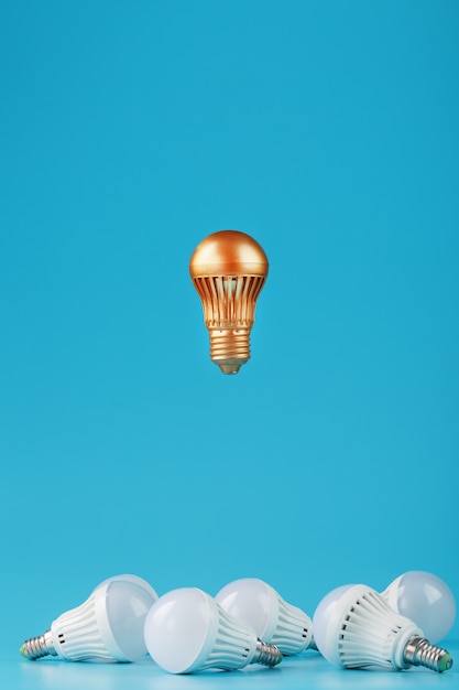 A prominent gold light bulb levitates above an environment of\
white led bulbs.