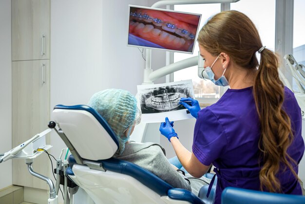 A promising dentist in a private clinic takes and shows pictures of teeth to his patient to prescribe treatment. Patient teeth concept shot