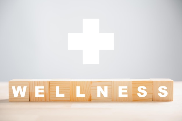 ウェルネス コンセプトという言葉が表示された木製の立方体ブロックで、ウェルネスとメンタルヘルスを促進します。ウェルネス コンセプトは、リラクゼーション ウェルビーイングとストレスのないライフスタイルを体現し、より健康的な生活を実現します。