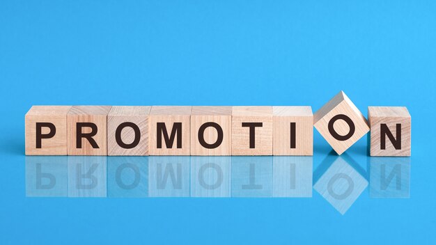 Promotion - word is made of wooden blocks lying on the blue table, business concept