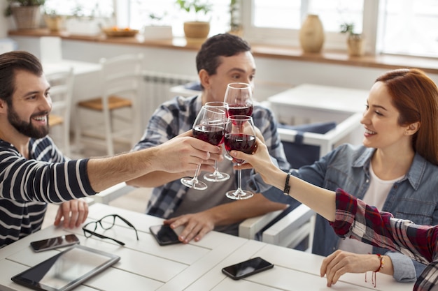 Proost. Goed uitziende vrolijke oude beste vrienden die samen aan tafel zitten en wijn drinken en praten