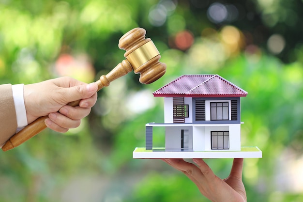 Property auction, Woman hand holding gavel wooden and model house on white 