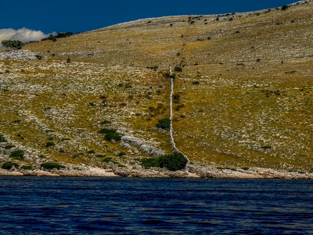 写真 クロアチアのコルナティ諸島国立公園の群島諸島にある財産の石の壁の境界線マーカー、海のボートからの風景