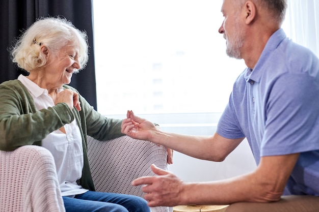 Proposal. senior man making a proposal and a happy woman smiling, grey-bearded man give golden ring to wife, at home