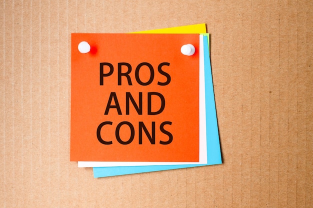 Pros and cons written on red paper and pinned on corkboard