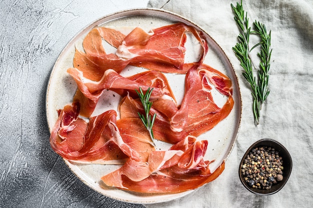 Prosciutto crudo, italian salami, parma ham. Antipasto plate. Gray background, top view.