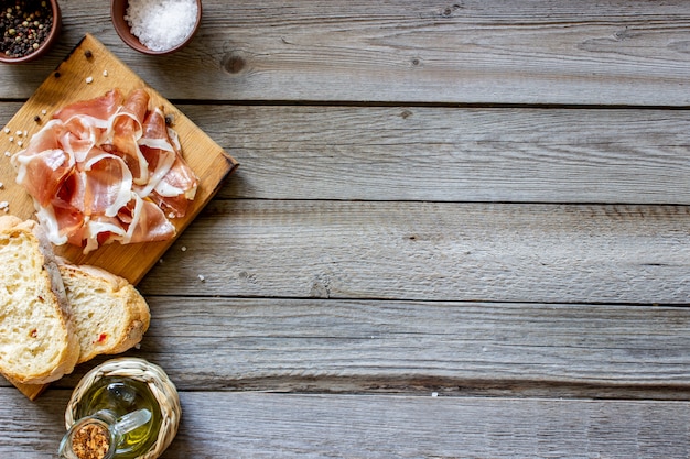 Prosciutto ham and bread on wood