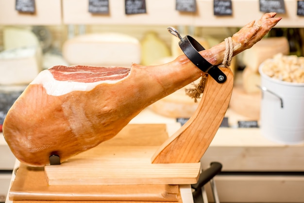 Photo prosciutto leg in ham holder on the table in the food store