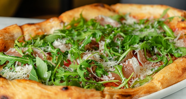 Prosciutto pizza with arugula in Roman style, Italian cuisine