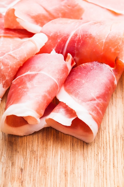 Prosciutto slices close up on the wooden table