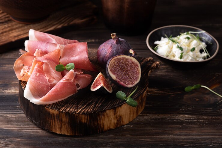 Photo prosciutto slices with figs on a dark wooden background, appetizer from dry cured ham, rustic style.