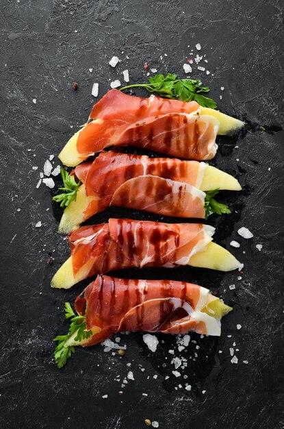 Prosciutto with melon on a stone plate Traditional Italian appetizer Top view Free copy space