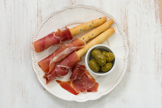 Prosciutto with olives on white plate