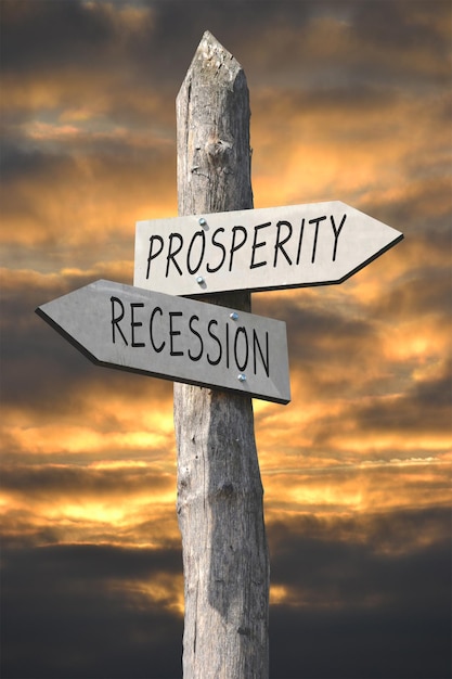 Prosperity and recession wooden signpost with two arrows and sunset sky