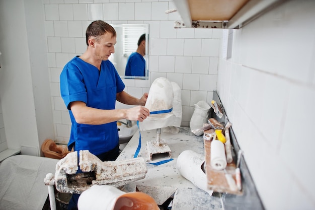 Prosthetist man making prosthetic leg while working in laboratory makes a model of plaster