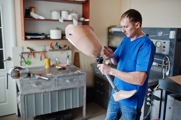 Prosthetist man making prosthetic leg while working in laboratory.