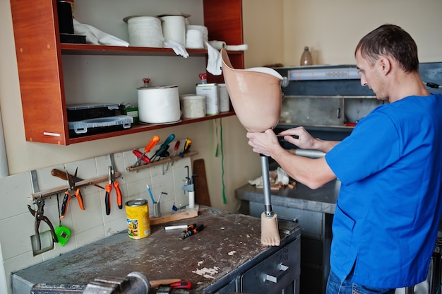 Prosthetist man making prosthetic leg while working in laboratory.