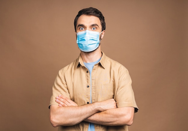 Protection against contagious disease, coronavirus, covid-19. Man wearing hygienic mask to prevent infection, airborne respiratory illness such as flu, 2019-nCoV. Isolated over beige background