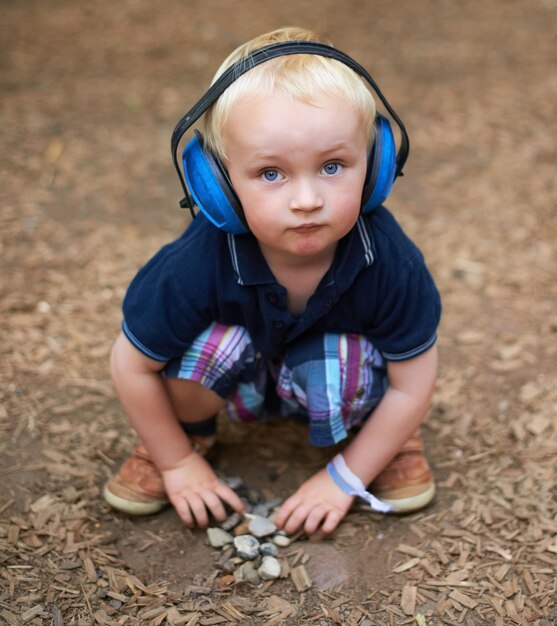 Photo protection boy and outdoor with headphones portrait and relax with nature playing and summer toddler kid and childhood with noise cancelling headset outside and sound in a park and safety