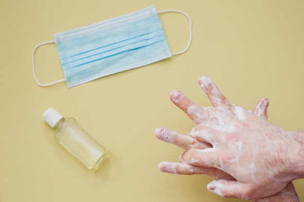 Foto protezione durante l'epidemia di virus concetto uomo che pulisce le mani con sapone e disinfettante per le mani su sfondo giallo