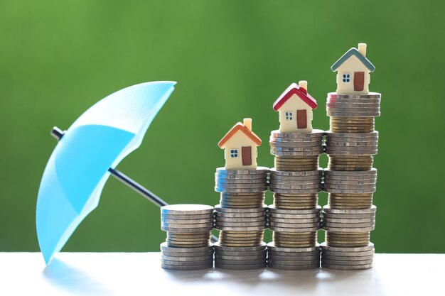 Protection, Model house on stack of coins money with the umbrella on nature green background,Finance insurance and Safe investment concept