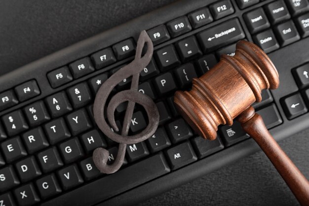 Protection of music as intellectual property. Treble clef on the keyboard next to the wooden gavel on black background. Music Licensing.