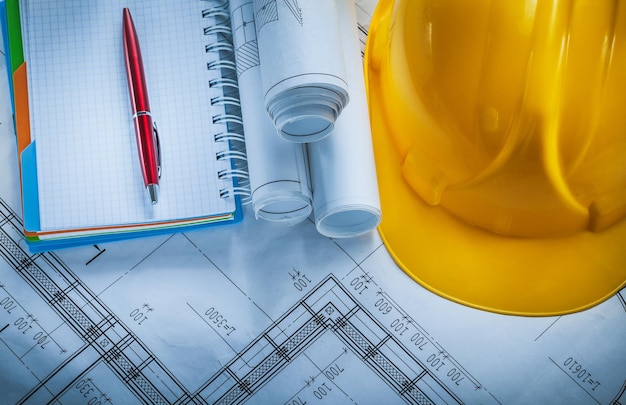 Protective building helmet checked notebook pen blueprints on construction plan