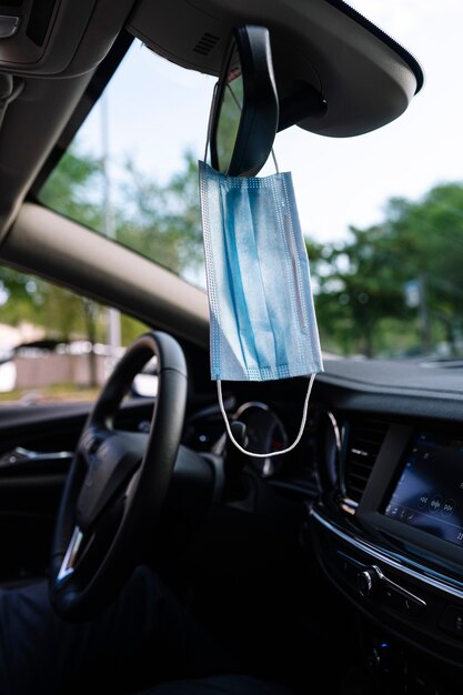 Защитная маска для лица, свисающая с зеркала заднего вида автомобиля