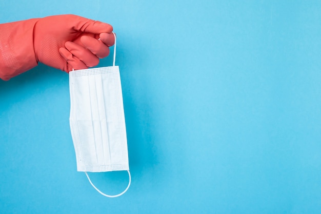 Protective face mask isolated on pink background in hand with gloves, copyspace, copyplace, space for text. Coronavirus, illness, infection, quarantine, medical mask