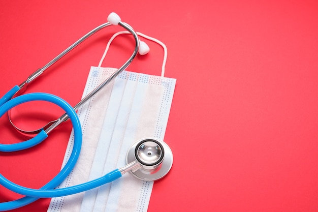 Photo protective face mask and stethoscope on red background