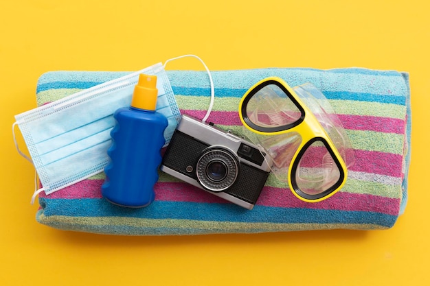 Protective face mask and suncream on a summer vacation beach towel