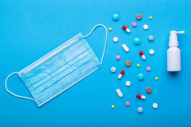 Protective face mask with multicolored pills and capsules on a blue background