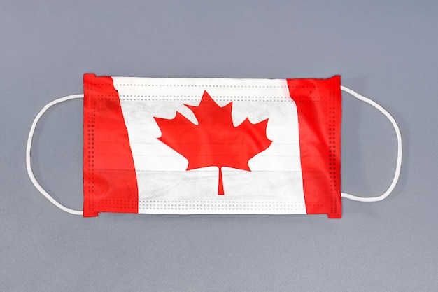 Protective gauze mask with flag of Canada on gray background Medical protective mask on gray background