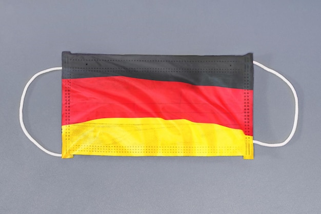 Protective gauze mask with flag of Germany on gray background Medical protective mask on gray background