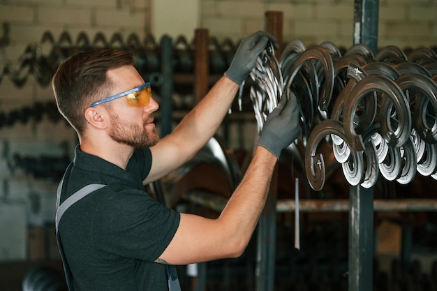 In protective glasses Man in uniform is in workstation developing details of agriculture technique